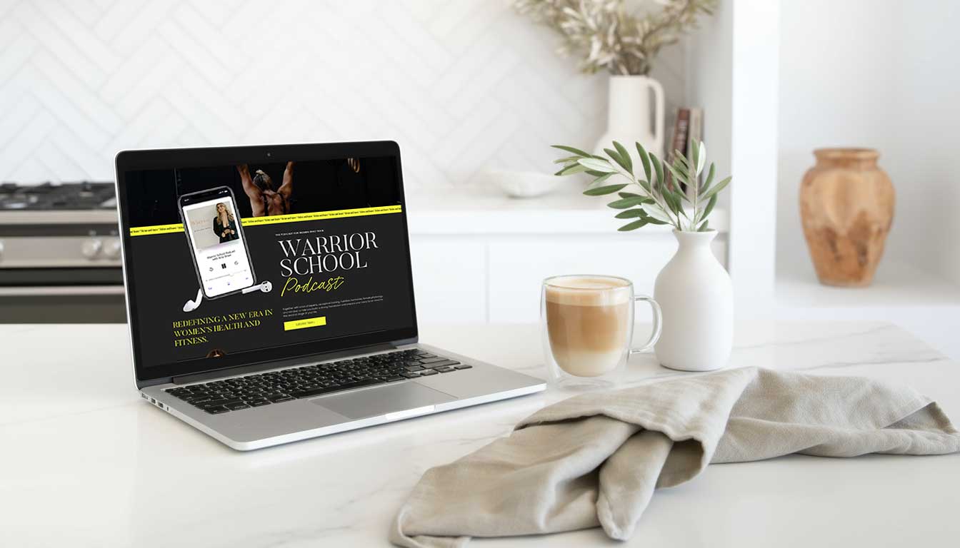 Laptop displaying Warrior School Podcast on a white kitchen counter.